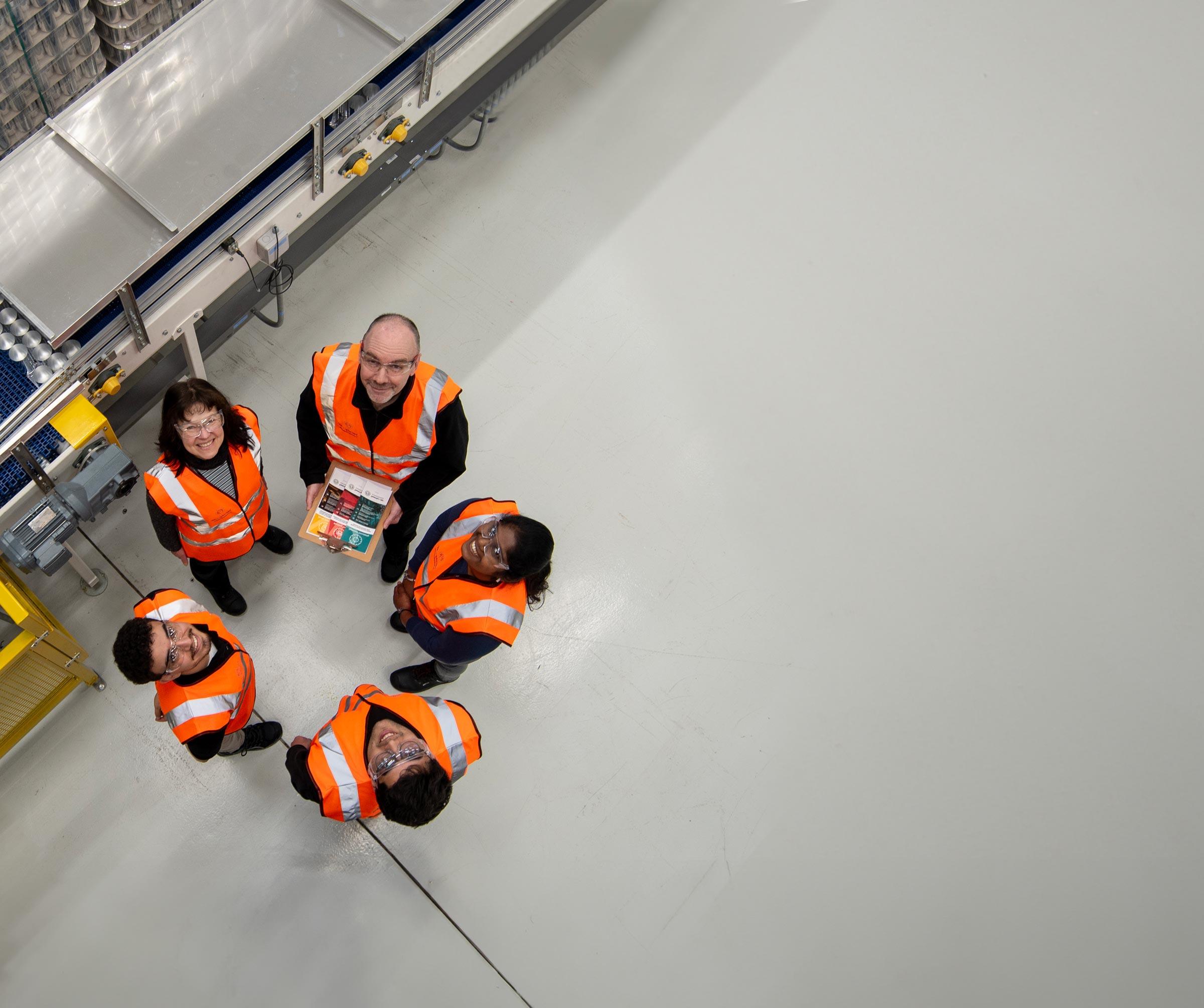 a group of five people standing in a circle look up at the camera